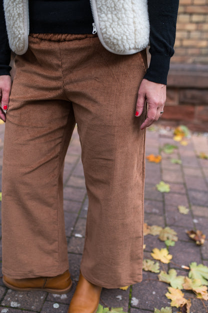Cord-Culotte in Cognac mit weitem, geradem Bein, Detailansicht von vorn mit Herbstlaub
