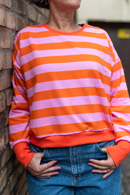 Gestreifter Sweatpullover mit orangem Bündchen am Saum, getragen zu Jeans