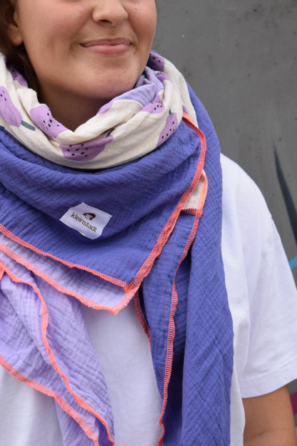 Frau trägt Musselinschal Lila, Birnen und Flieder mit Neonorange-Naht, über weißem Shirt